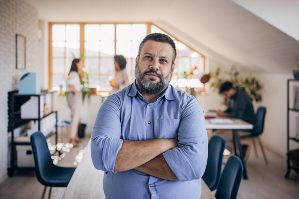 Diverse group of people, portrait of a Caucasian man standing in front of his colleagues in modern office.