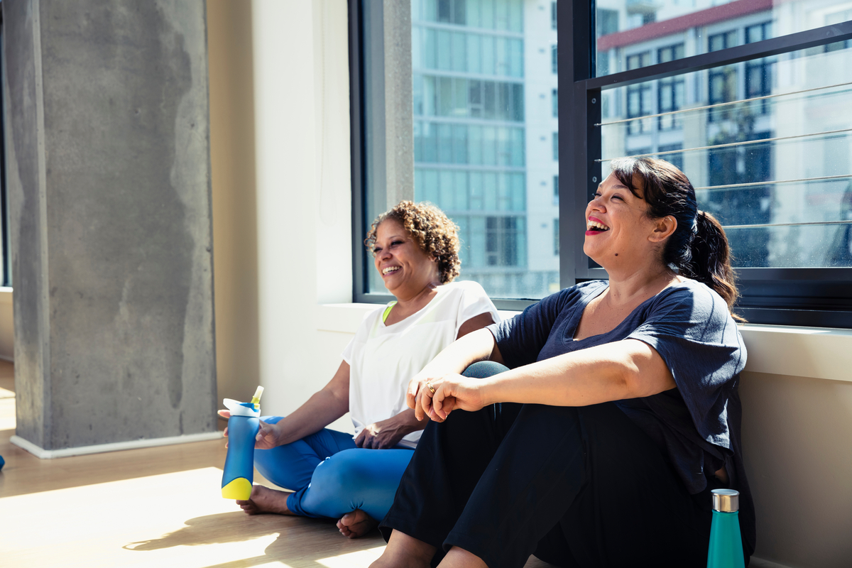 Two women sitting against the wall after a hard workout