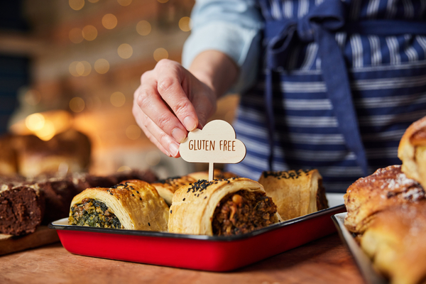 Sales Assistant In Bakery Putting Gluten Free Label Into Freshly Baked Savoury Roll