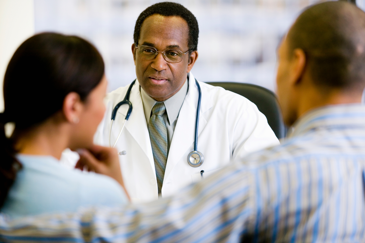 Provider sitting down with a patient and their partner. 