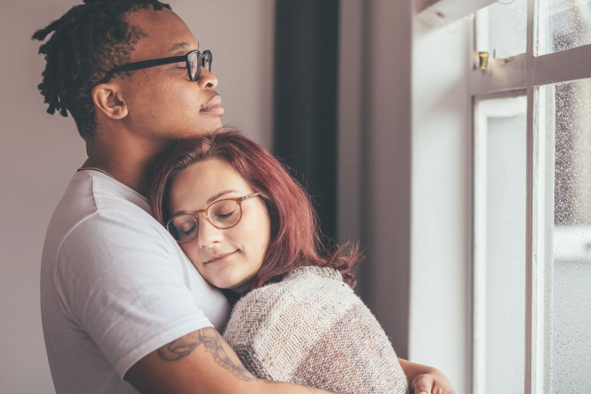 Interacial couple embracing by a window