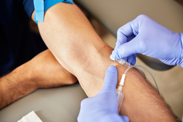 Image of a person getting their blood drawn. Medical professional is wearing gloves