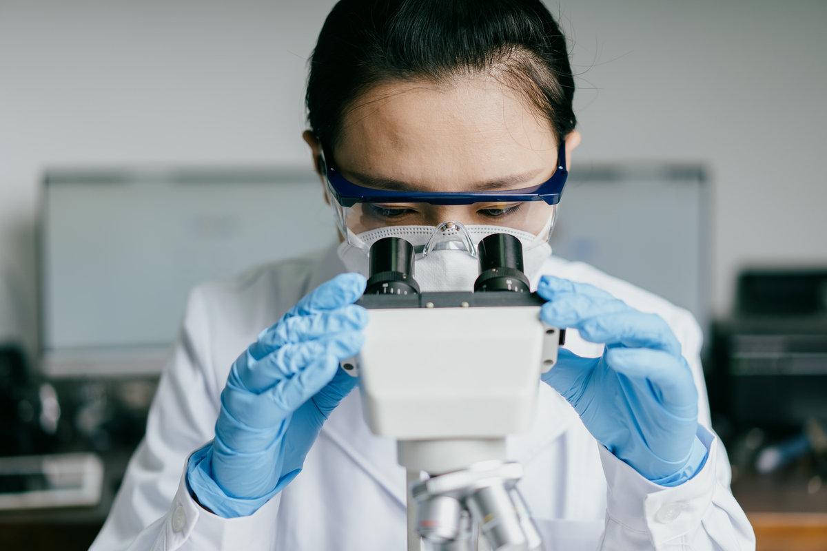 Scientist looking into a microscope. Angle of photo is straight forward