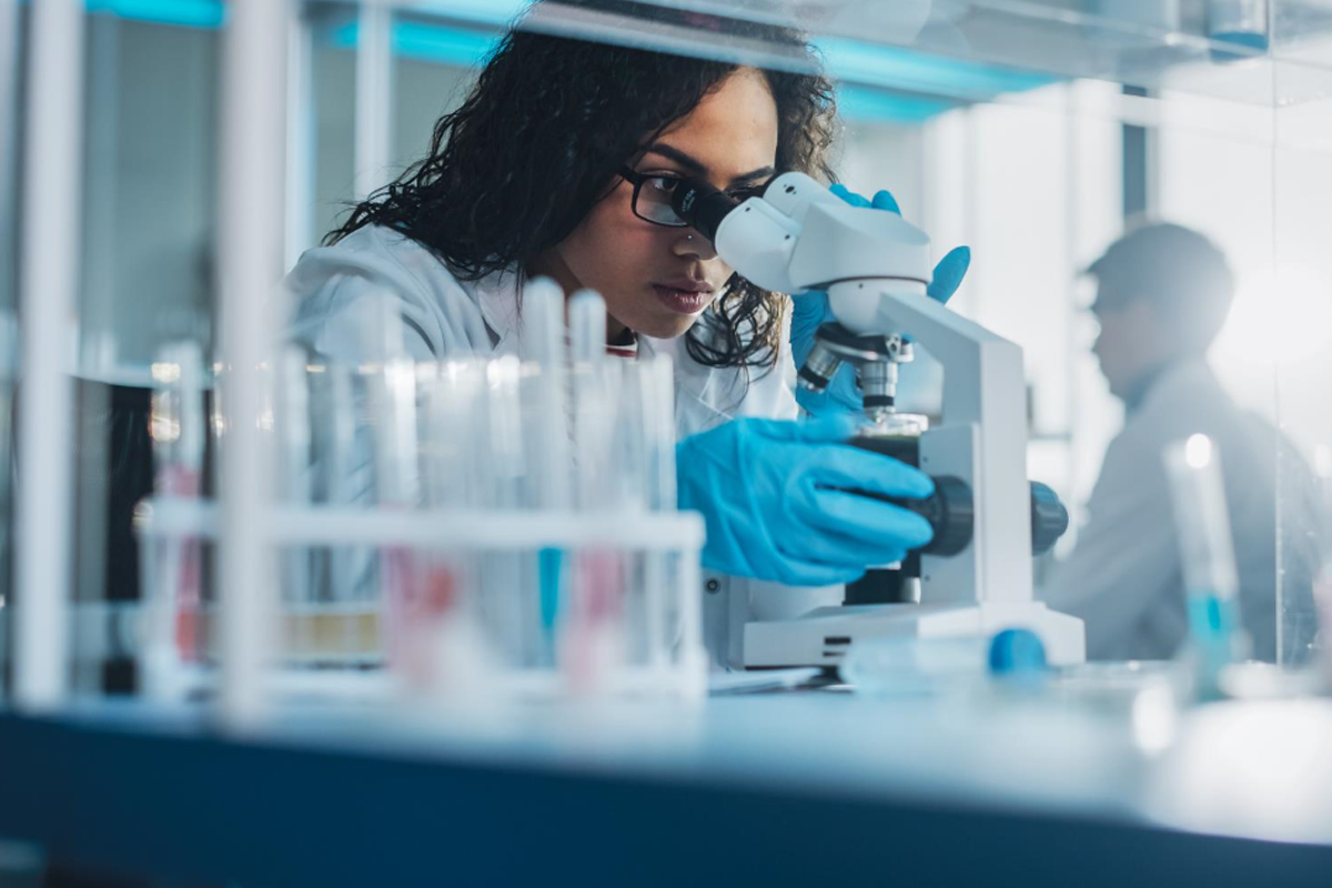 scientist looking into a microscope with PPE